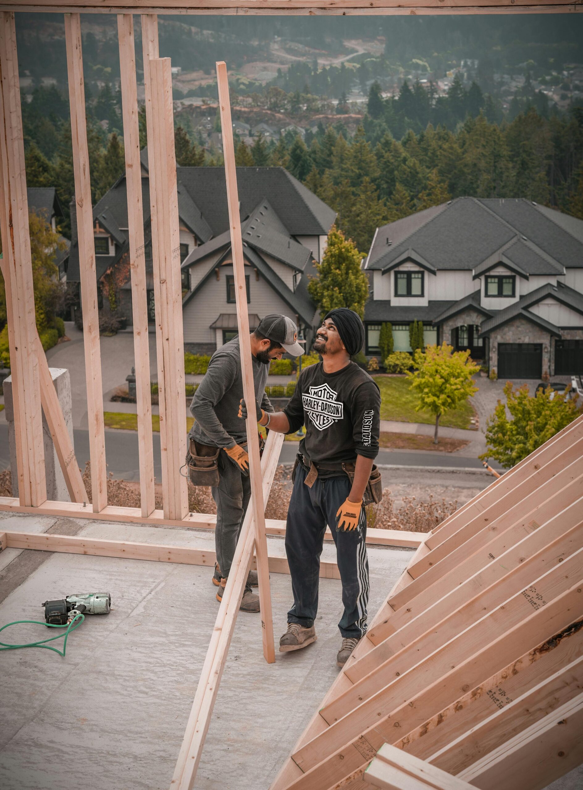 Two workers on a construction site in Vancouver, BC, assembling a wooden frame for residential housing.