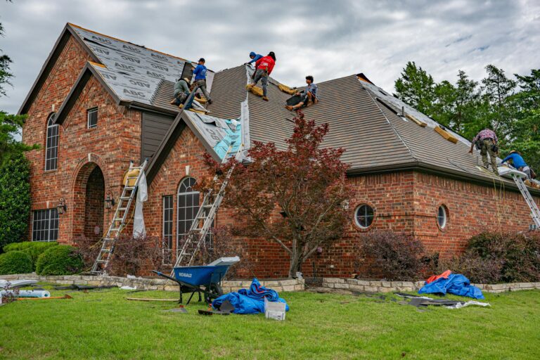Roofers working on brick home in Allen, Texas, addressing shingles and roofing materials.
